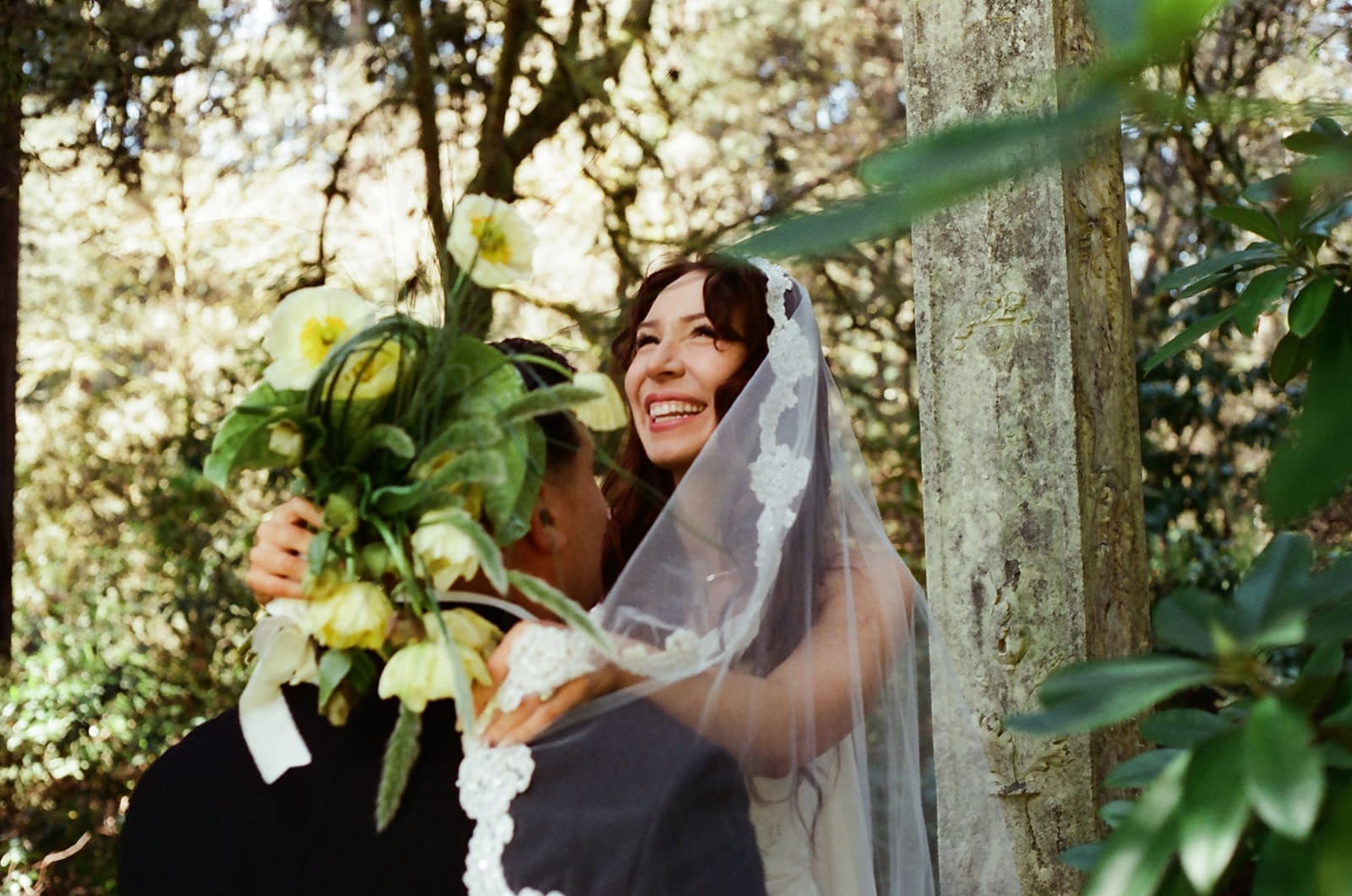 Bride laughing while embracing the groom among lush greenery at Lakewold Gardens, photographed on CineStill 400D film.