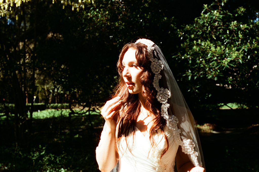 Bride standing in dramatic sunlight and shadow among the gardens at Lakewold Gardens, photographed on CineStill 400D film.