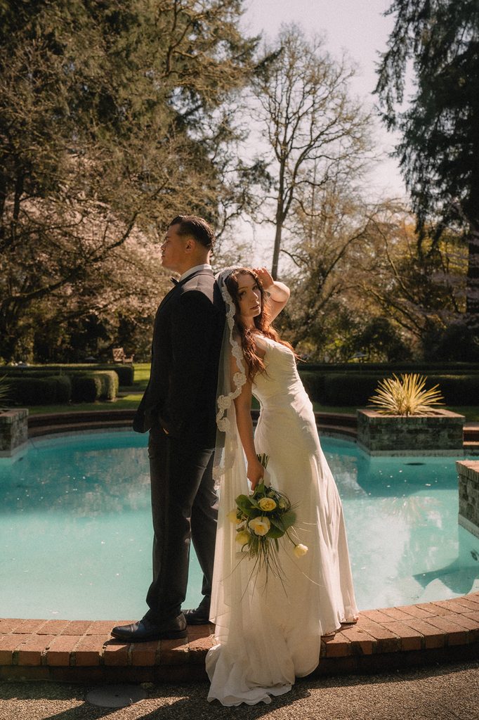 Bride and groom posing in front of the pool for their Lakewold Gardens wedding photos in Lakewood, Washington.