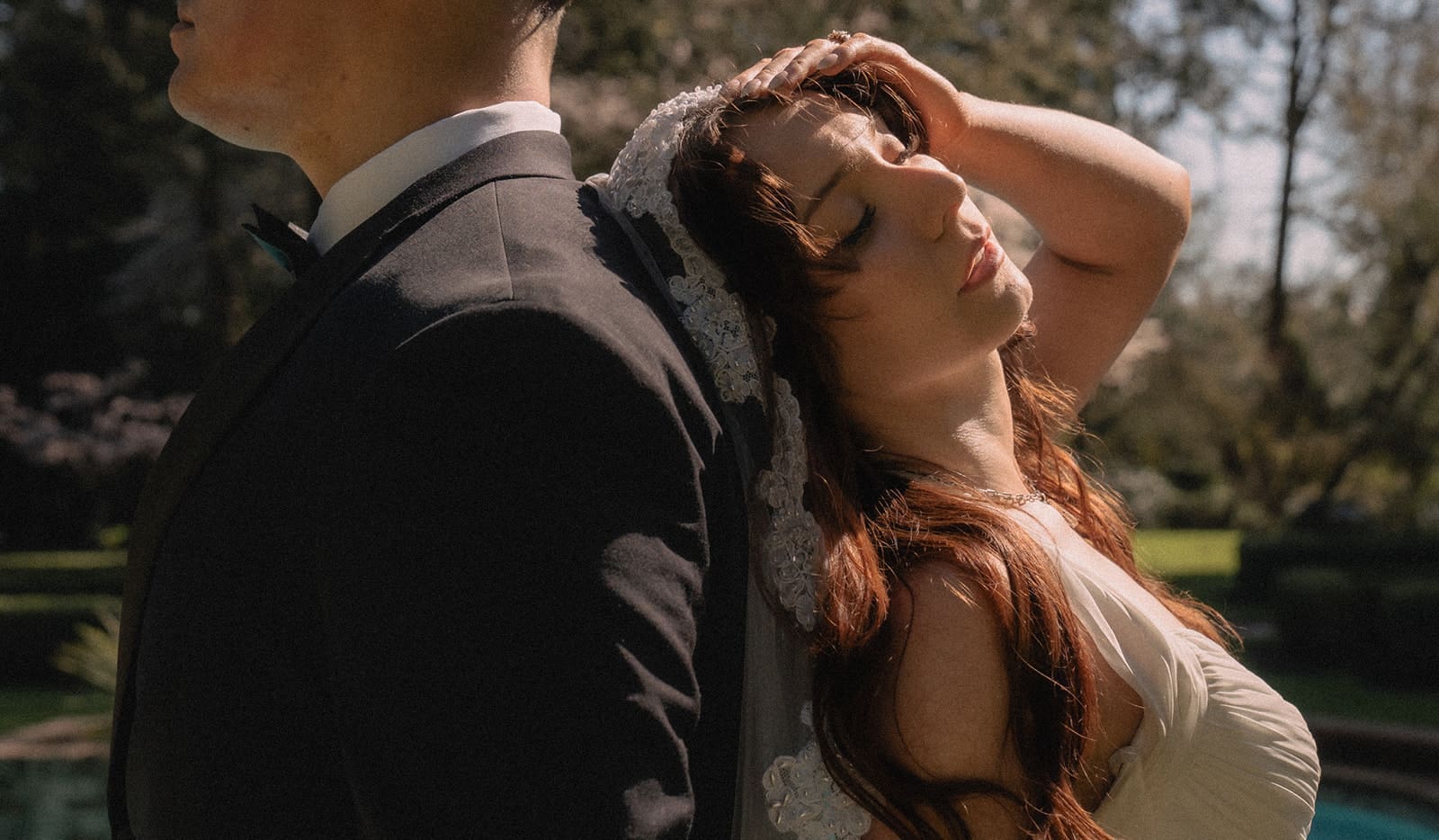 Close up shot of a bride and groom posing with their backs to one another.