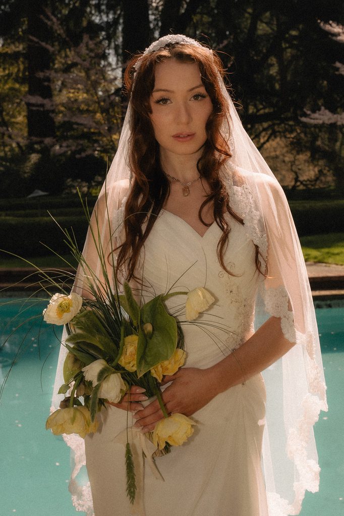 Bride holding a bouquet and posing in front of the pool for her Lakewol Gardens wedding photos in Lakewood, Washington.