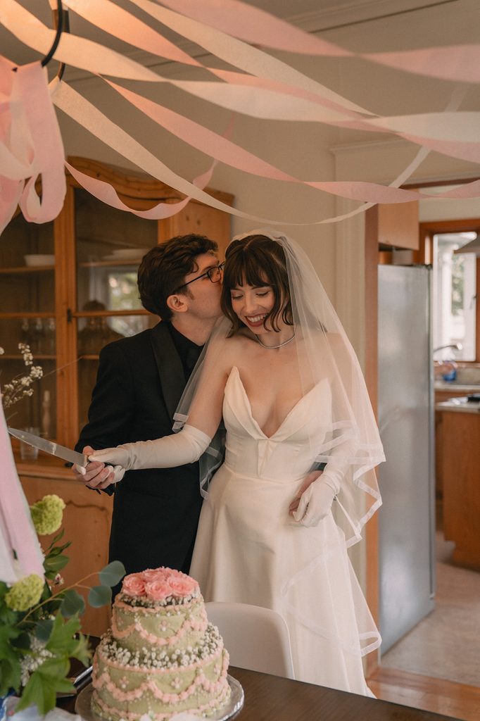 Newlyweds smiling together while cutting their wedding cake at an intimate Seattle micro wedding