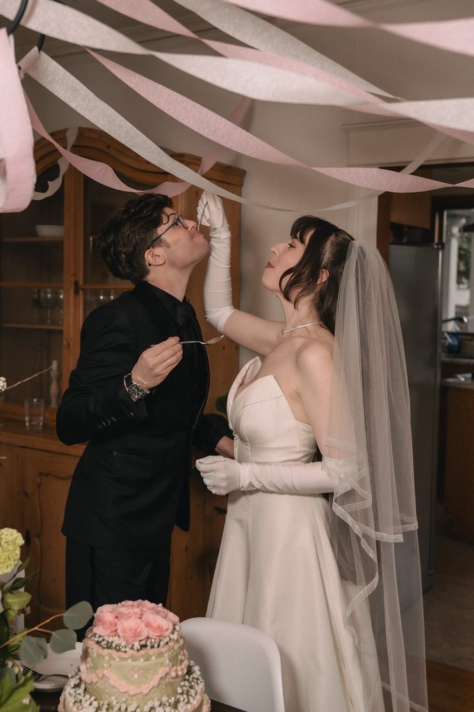 Bride playfully feeding cake to the groom during their intimate wedding reception