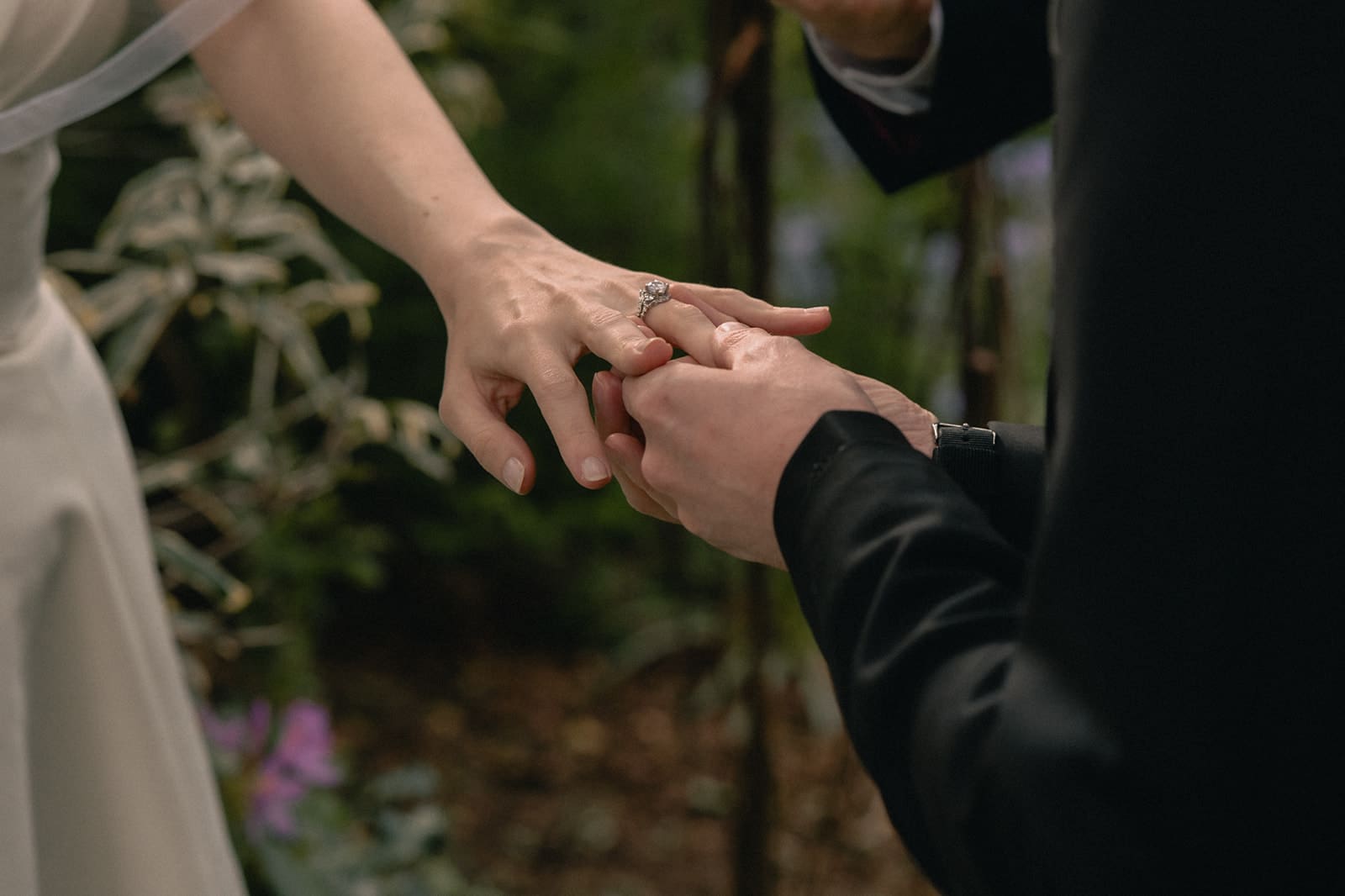 Groom putting a ring on his brides finger during their Seattle micro wedding ceremony at an Airbnb.