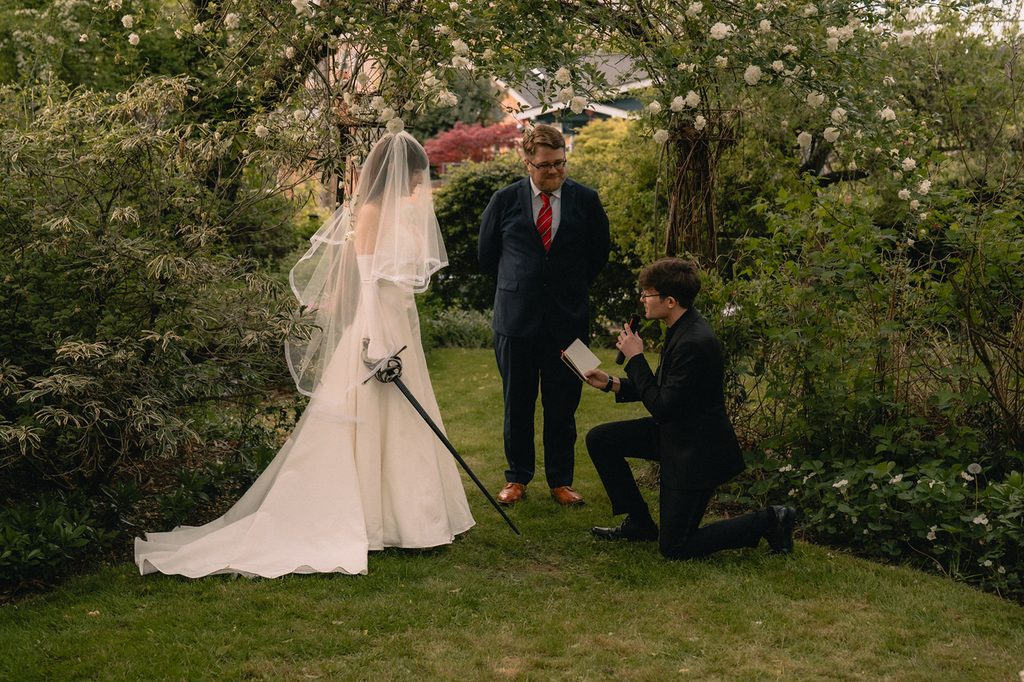Groom kneeling as he reads vows to the bride. 