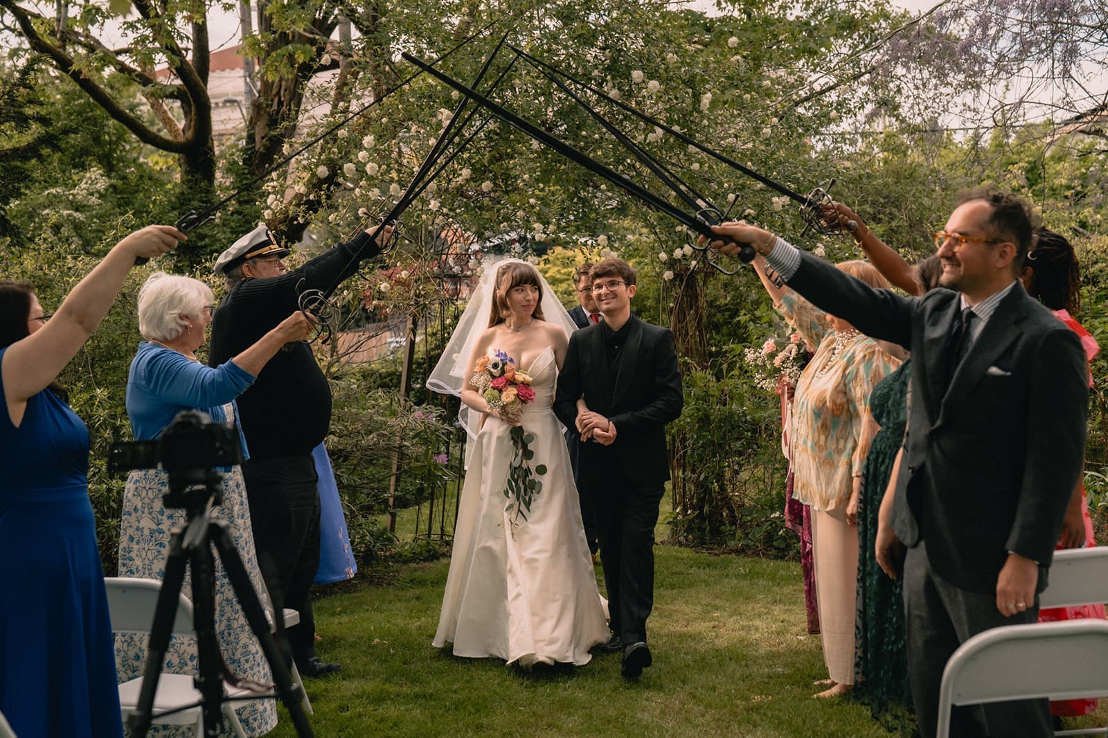 Bride and groom walking back down the aisle under an arch of swords after their Seattle micro wedding ceremony at an Airbnb.