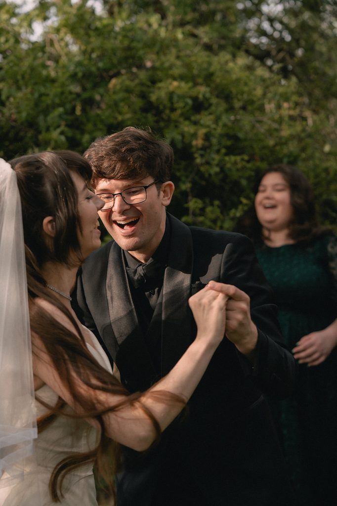 Bride and groom laughing as they dance.