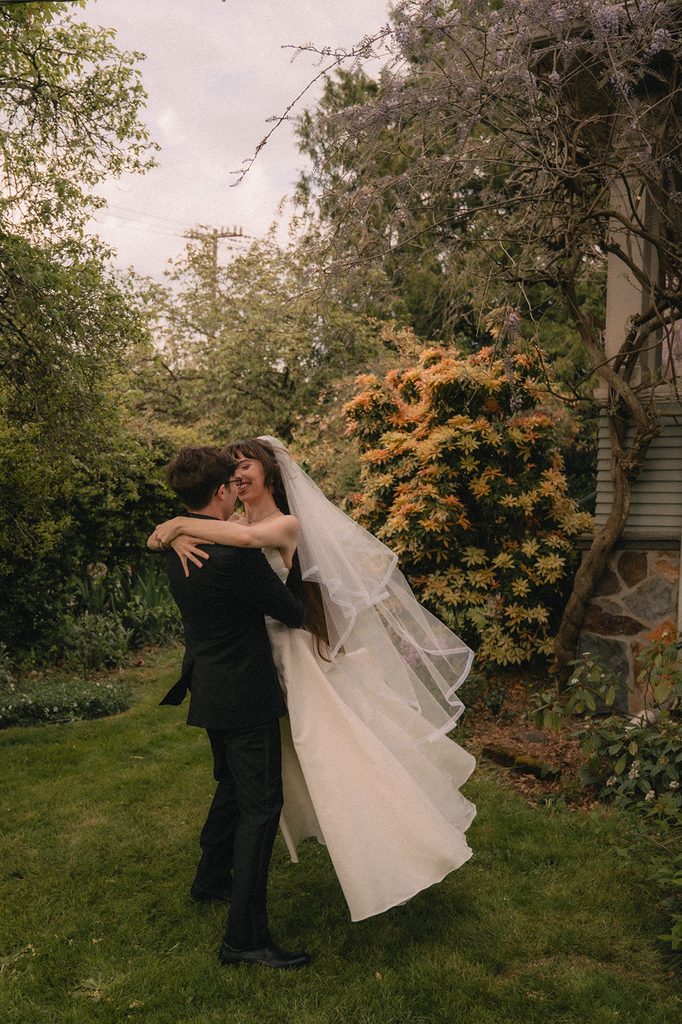 Groom lifting his bride during their outdoor portraits from a Seattle micro wedding at an Airbnb.