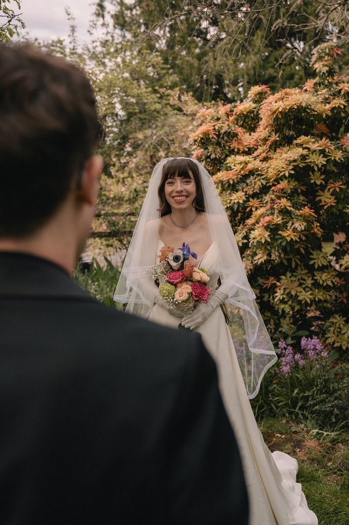 Groom with his back to the camera as his bride looks at him smiling.