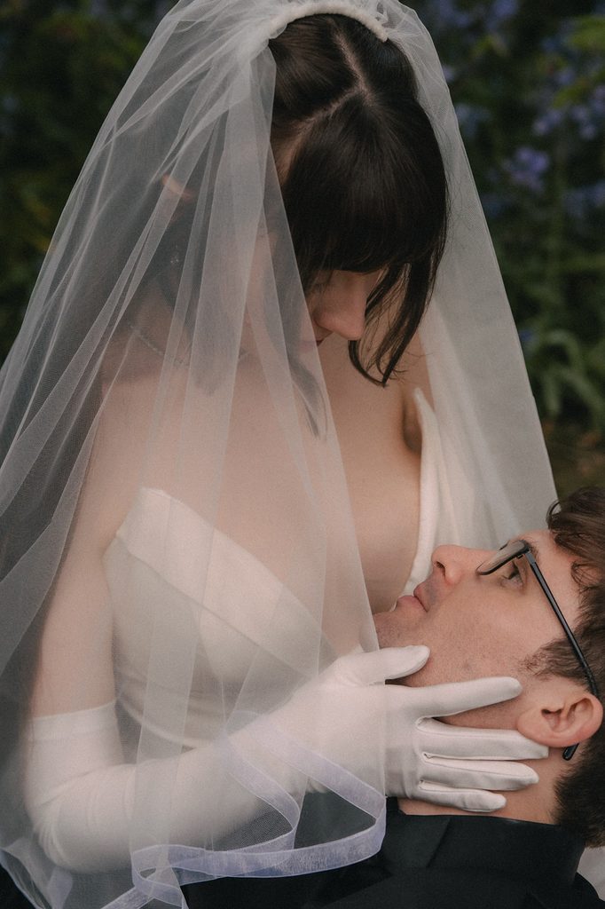 Bride caressing her grooms face lovingly during their outdoor portraits. 