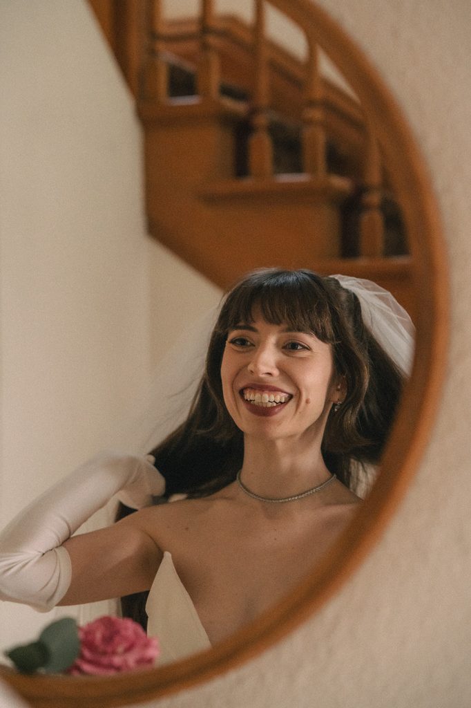 Bride smiling at herself in the mirror.