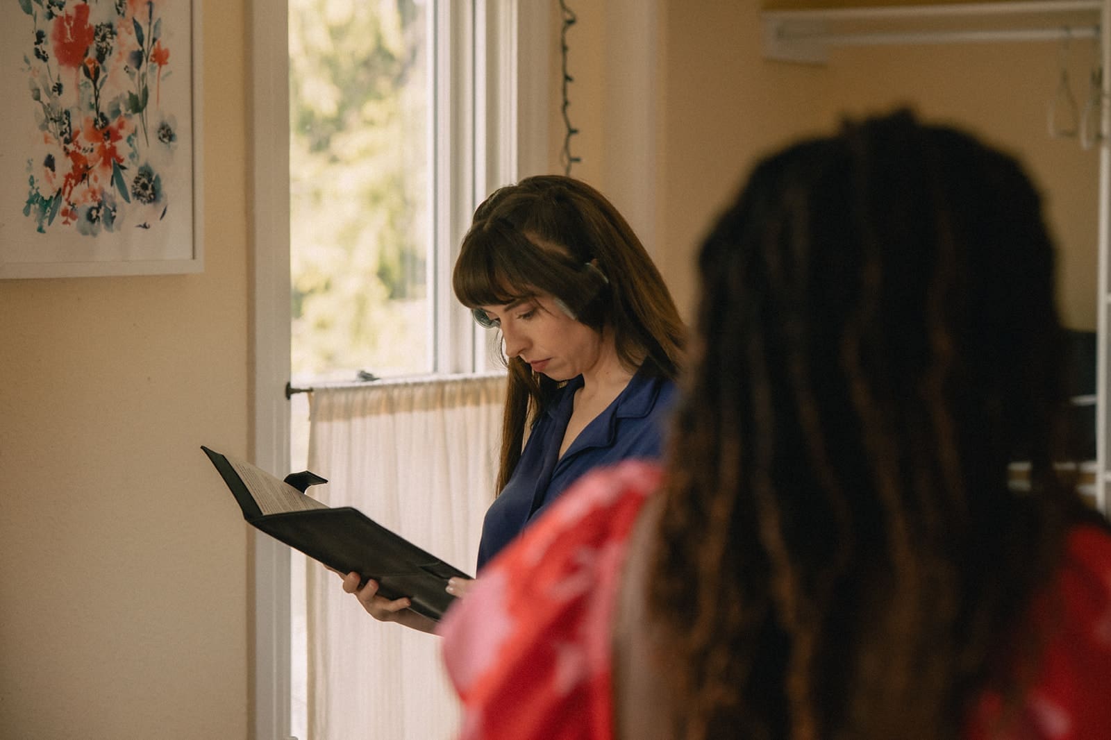 Bride reading a paper as she gets ready. 