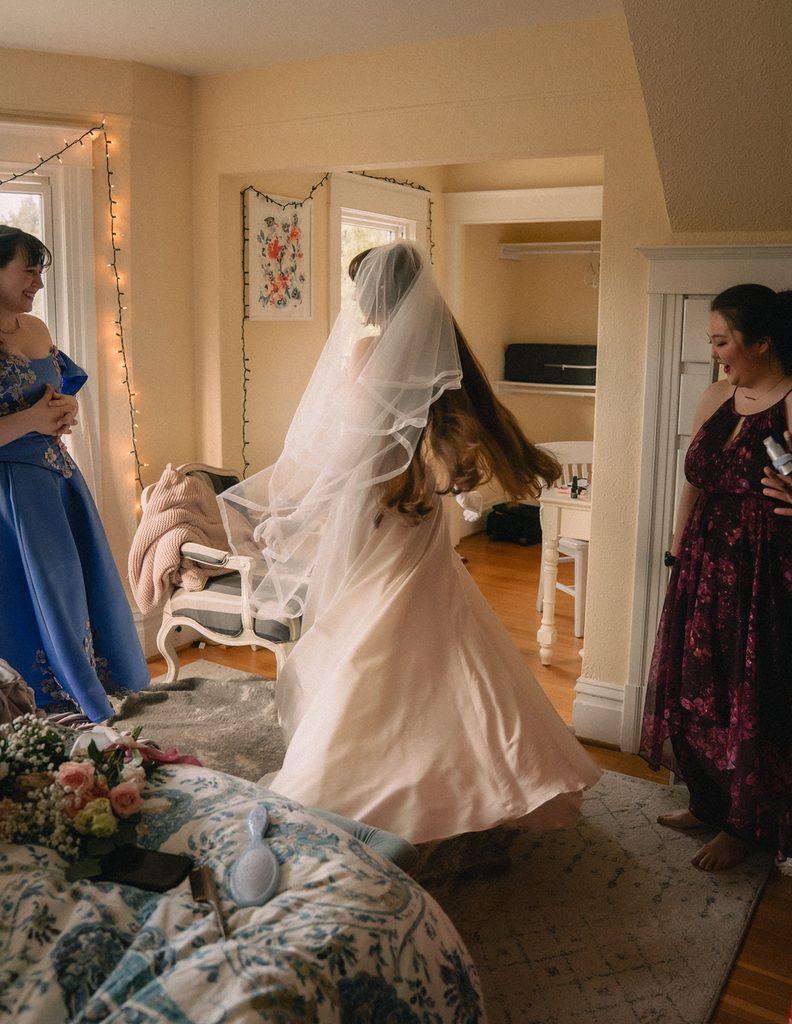Bride twirling in her dress and veil as she gets ready for her Seattle micro wedding at an Airbnb.