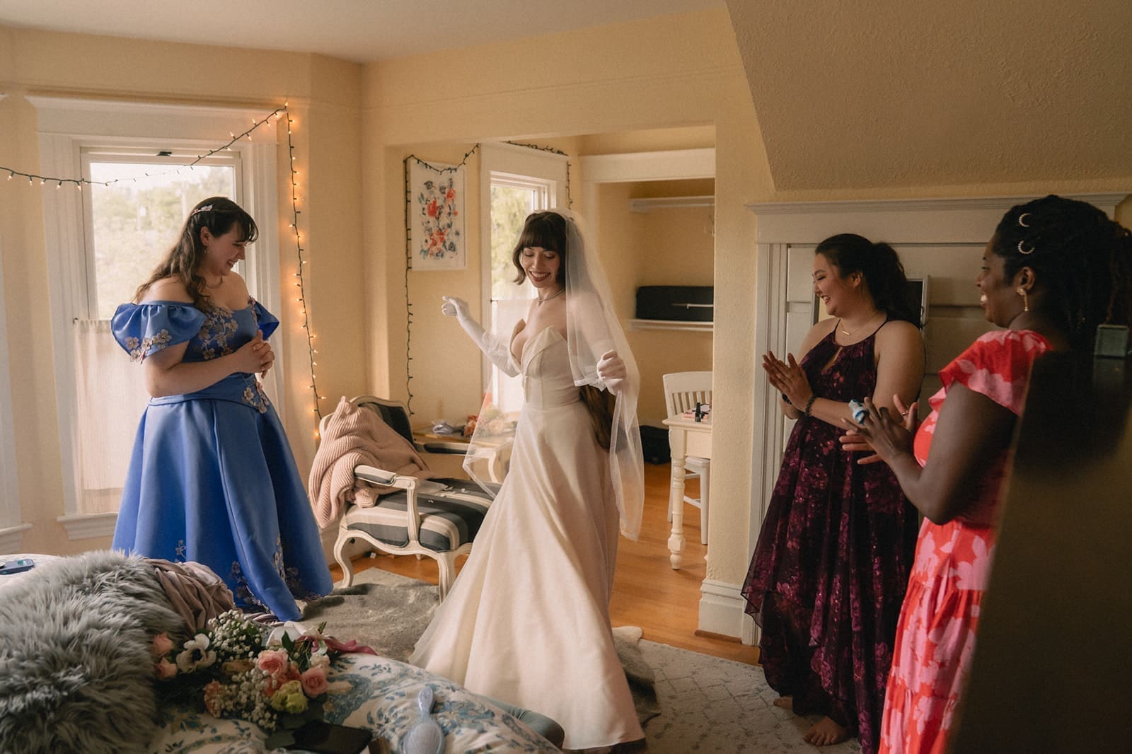 Bride twirling in front of her bridesmaids in her dress and veil. 