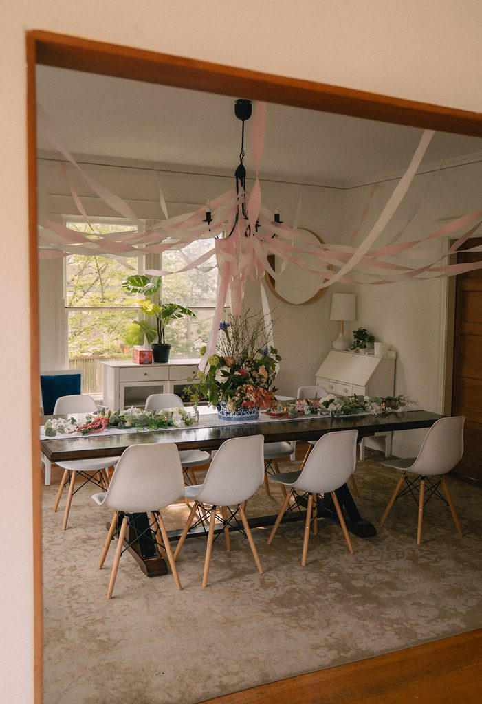 Intimate Airbnb wedding reception setup with pink streamers, florals, and a long dining table