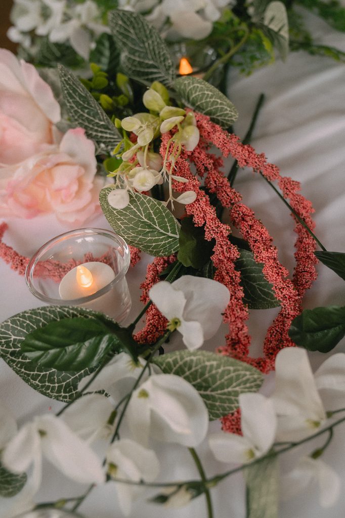Close-up of pink and white floral table decor with greenery and candlelight